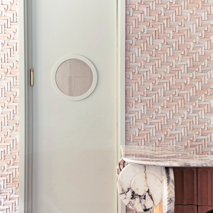 Marble table in a room with a white door and light pink Botteganove Haiku tiles at the wall